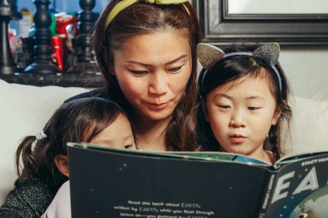 Mother reading a book to her 2 daughters